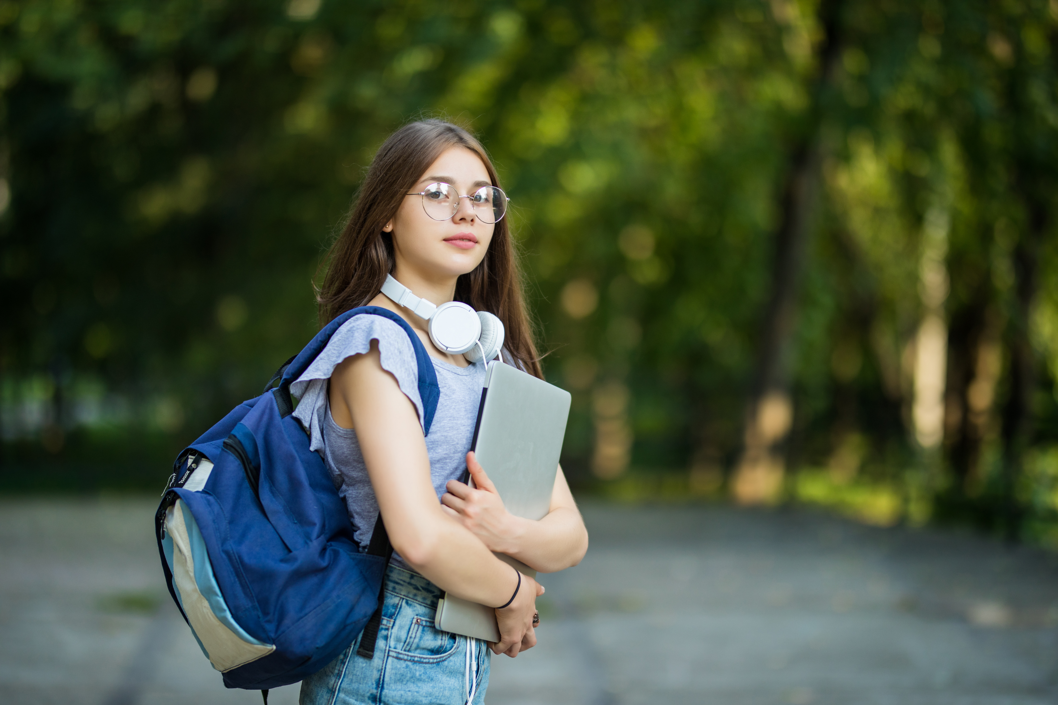 cheerful-attractive-young-woman-with-backpack-notebooks-standing-smiling-park
