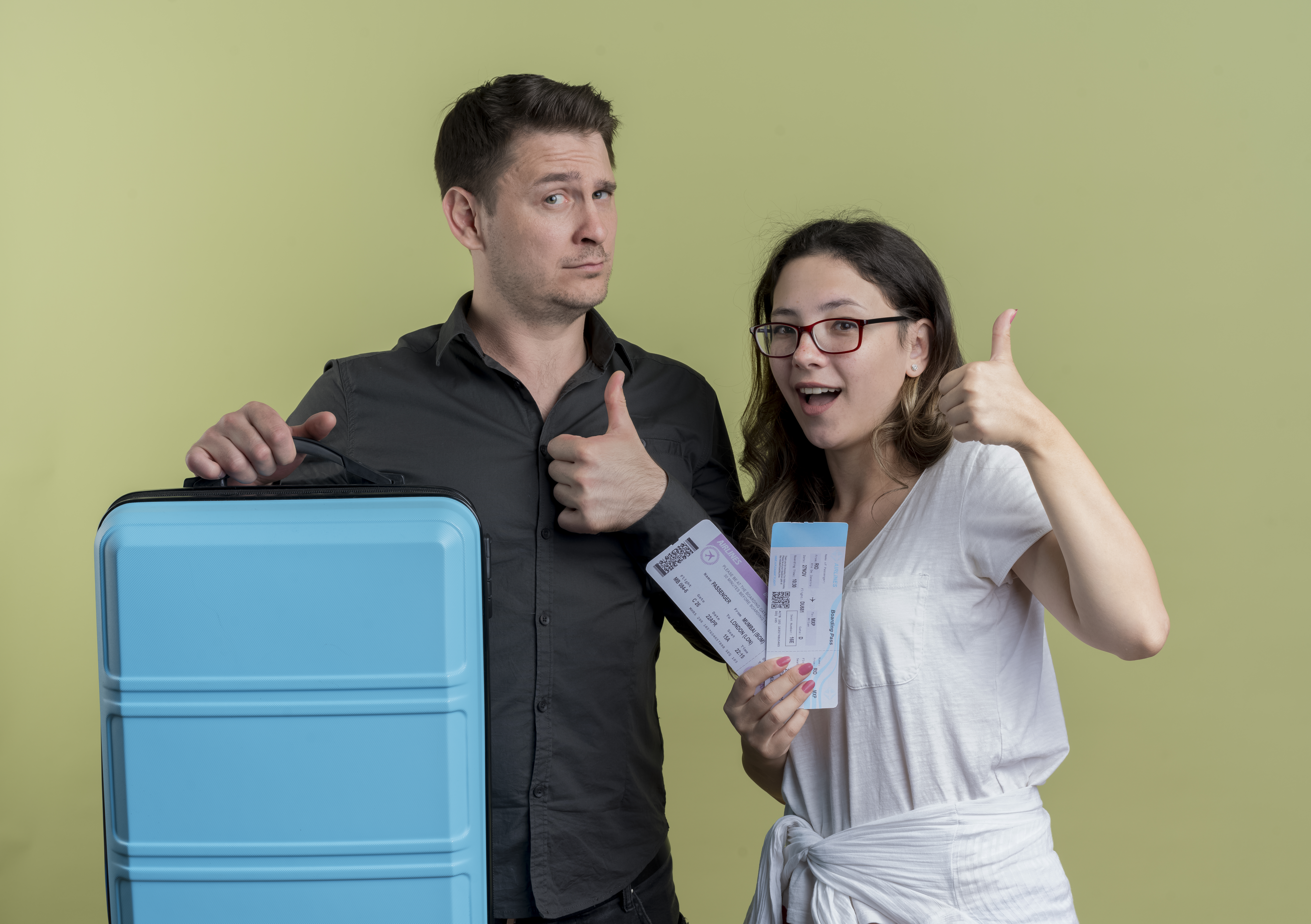 happy-young-couple-tourists-man-woman-holding-suitcase-smiling-showing-thumbs-up-standing-light-wall
